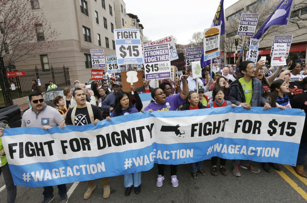 Fast-food restaurant employees and other workers marched in a "Fight for 15" demonstration in Boston in 2015. The Massachusetts minimum wage will rise to $12 per hour on Jan. 1 and gradually increase to $15 per hour in 2023. (Steven Senne/AP)