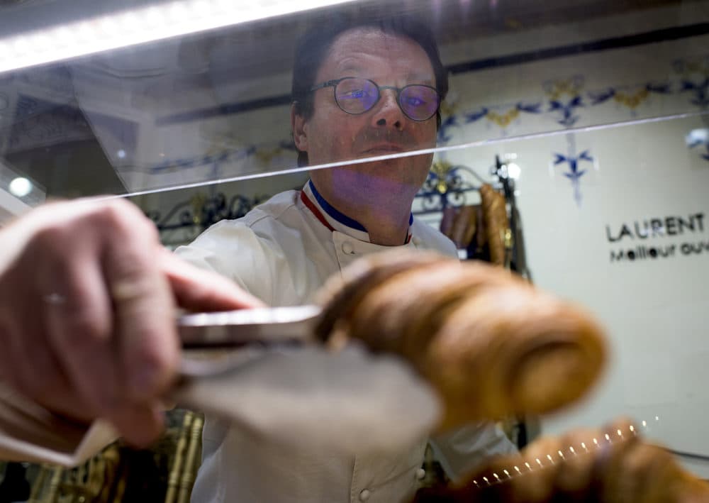 Laurent Duchêne, who has been decorated as one of France's top pastry chefs, replenishes croissants in a case at his boutique in the 13th arrondissement on Nov. 12, 2018 in Paris. (Pete Kiehart for Here & Now)