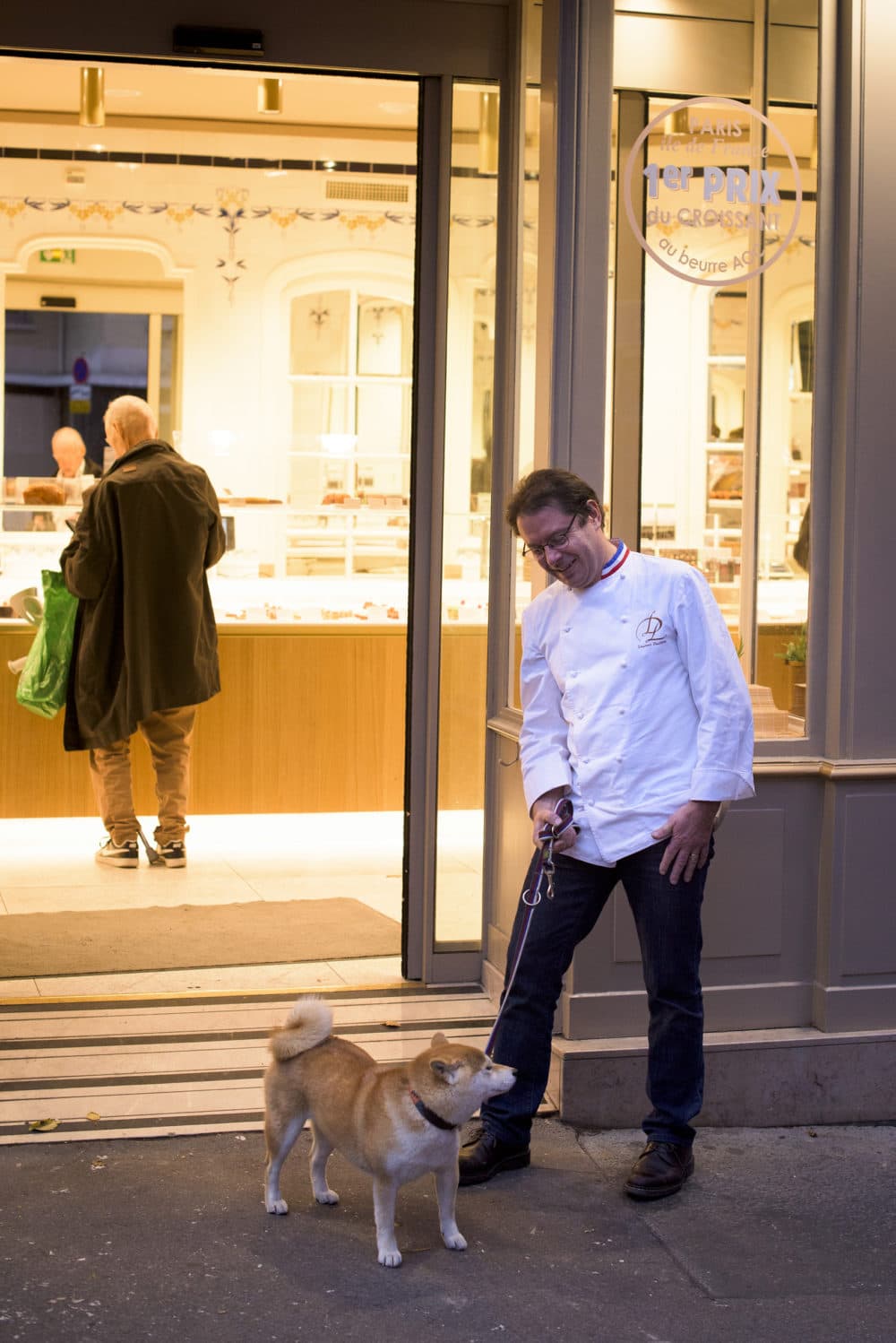 Laurent Duchne, who has been decorated as one of France's top pastry makers, watches a patron's dog, who is named Jacynthe, outside his boutique in the 13th arrondissement on Nov. 12, 2018 in Paris. (Pete Kiehart for Here & Now)