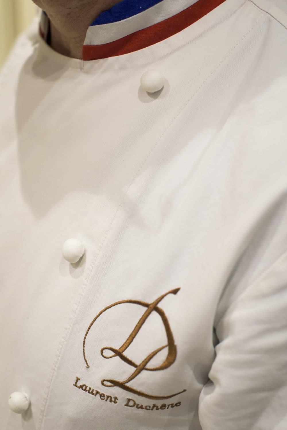 Laurent Duchne, who has been decorated as one of France's top pastry makers, poses for a photo at his boutique in the 13th arrondissement on Nov. 12, 2018 in Paris. The tricolor collar on his jacket denotes his status as a Meilleur Ouvrier de France. (Pete Kiehart for Here & Now)