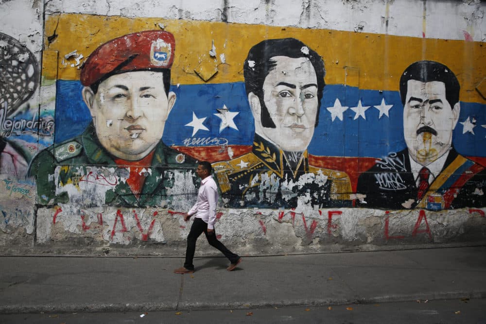 A man walks past a mural depicting Venezuela's late President Hugo Chávez, Latin American independence hero Simon Bolivar and Venezuela's President Nicolás Maduro on Jan. 30, 2019 in Caracas, Venezuela. (Marco Bello/Getty Images)