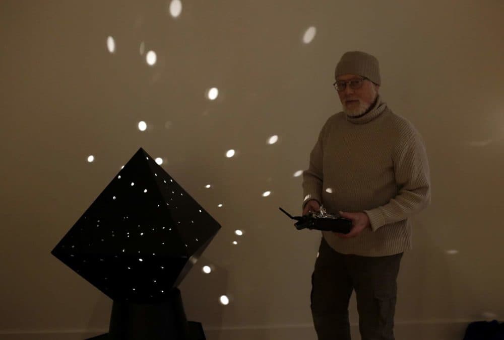 Sculptor John Powell stands with Otto Piene's diamond light robot as he helps with the installation process at the Fitchburg Art Museum. (Hadley Green for WBUR)