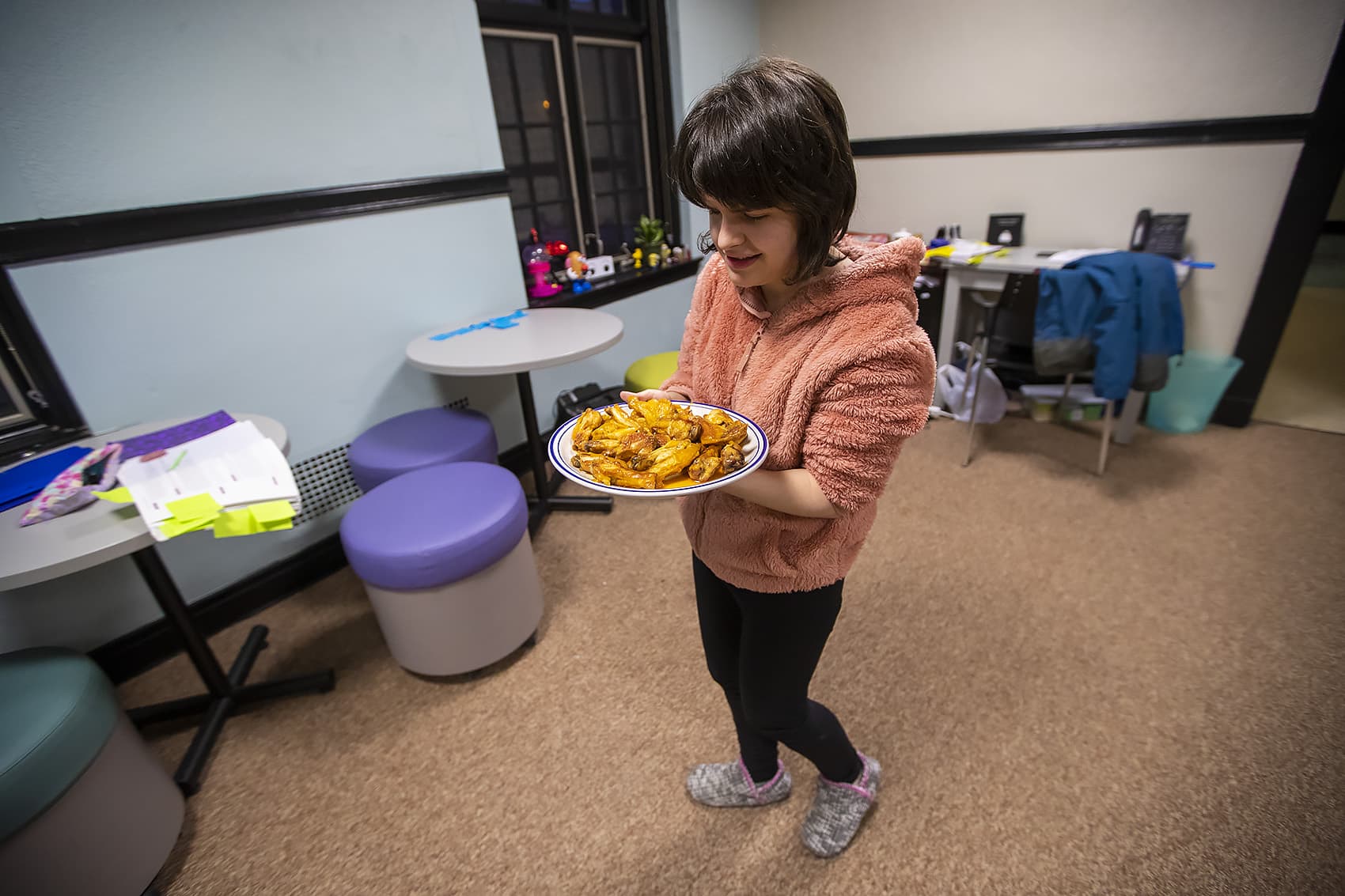 Jordan Scheffer brings the finished buffalo wings into the living room where the students will serve the food and watch the game. (Jesse Costa/WBUR)