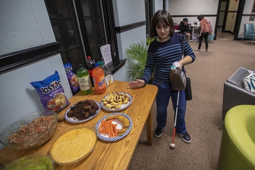 Haley Valente feels for a spot to place the iced tea being served at the party. (Jesse Costa/WBUR)