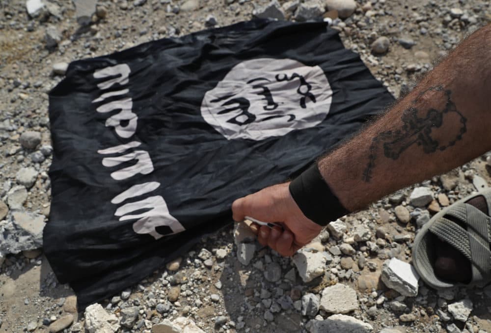A fighter of Christian Syria militia that battles the Islamic State group under the banner of the U.S.-backed Syrian Democratic Forces, burns an ISIS flag on the front line on the western side of Raqqa, Syria, in July 2017. (Hussein Malla/AP)