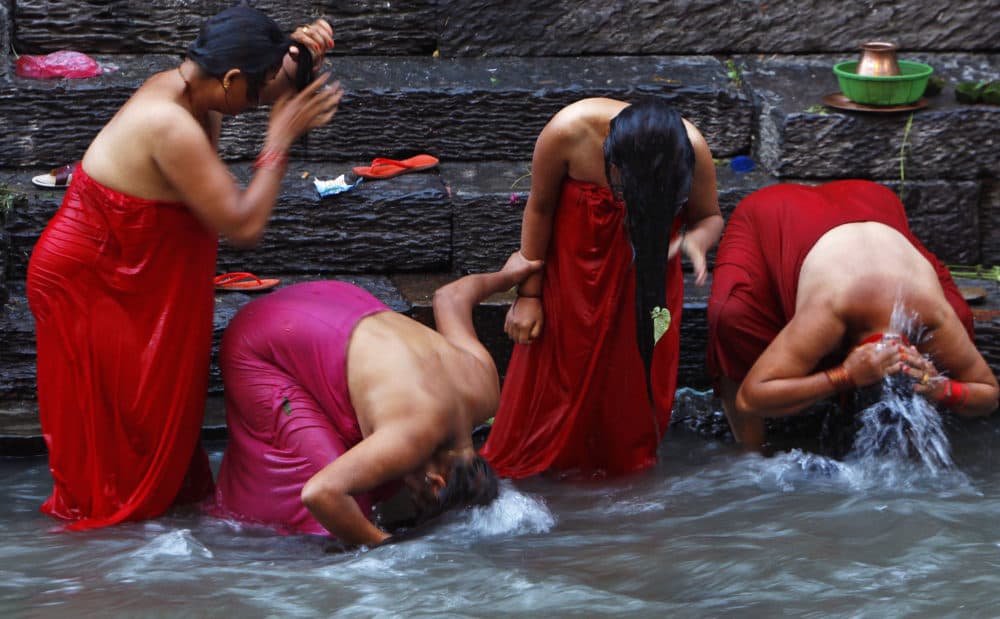 In this Sept. 10, 2013 file photo, Nepalese Hindu women bathe in the Bagmati River on Rishi Panchami, a day when rituals are performed to wash away sins committed during menstruation period, a period considered impure, in Katmandu, Nepal. Many menstruating women are still forced to leave their homes and take shelter in unhygienic or insecure huts or cow sheds until their cycle ends, though the practice, called Chhaupadi, was actually outlawed a decade ago. (Niranjan Shrestha/AP)