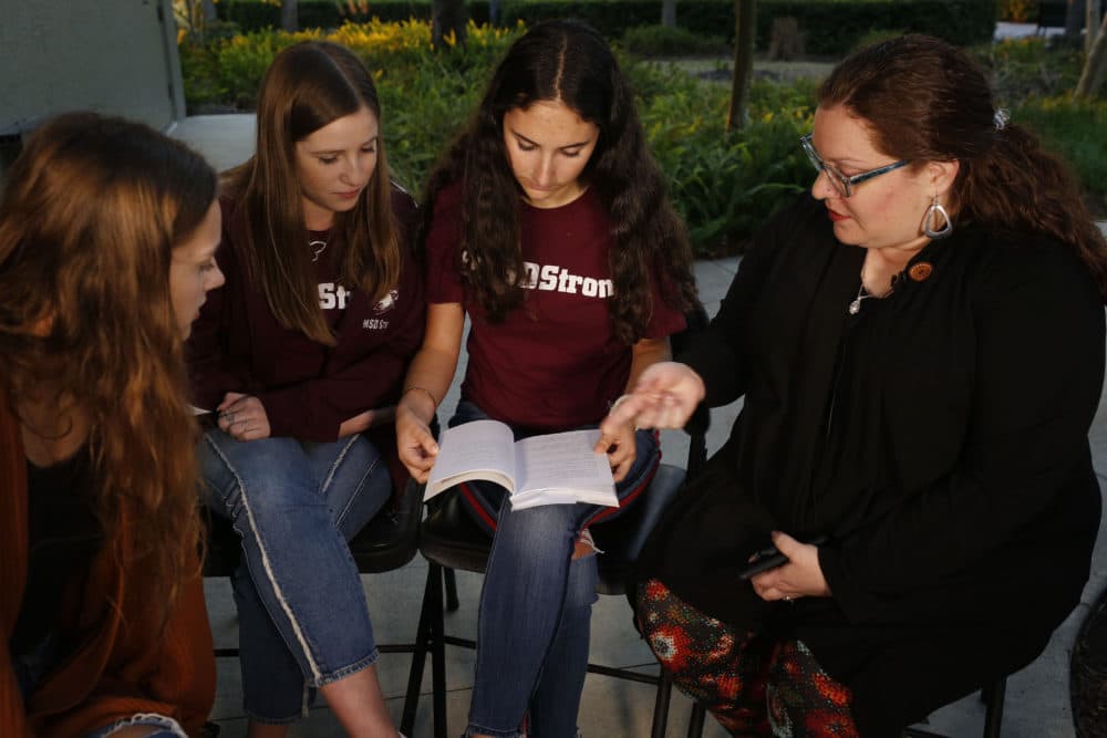 In this Wednesday, Jan. 16, 2019 photo, Brianna Jesionowski, from far left to right, Brianna Fisher and Leni Steinhardt sit during an interview, as journalism teacher Sarah Lerner, right, makes a point regarding the new book called "Parkland Speaks: Survivors from Marjory Stoneman Douglas Share Their Stories." Students and teachers from the Florida school, where 17 died in  Feb. 2018 mass shooting, wrote the raw, poignant book about living through the tragedy. (Brynn Anderson/AP)