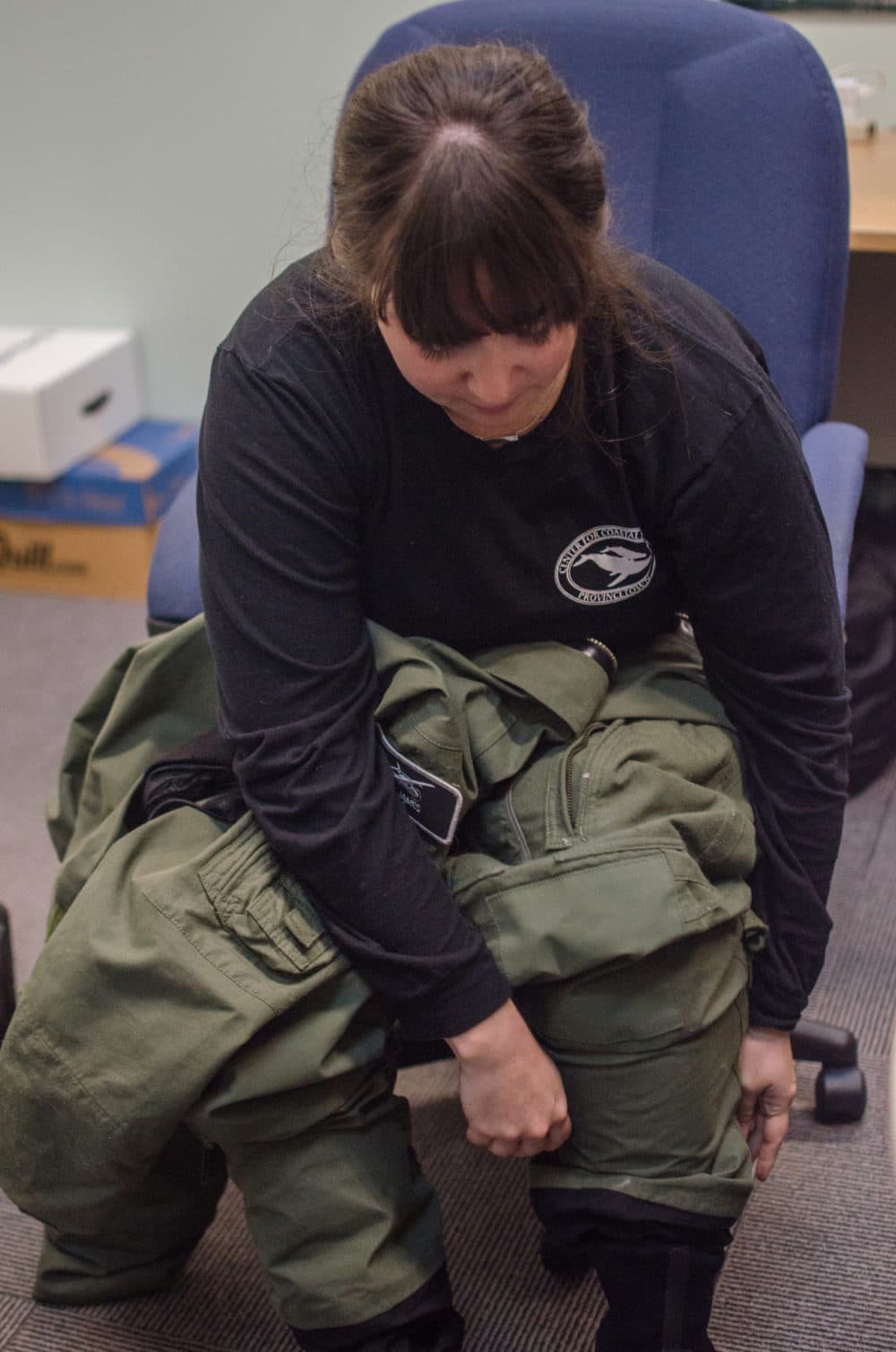 Amy James puts on her flight suit before a survey. (Sharon Brody/WBUR)