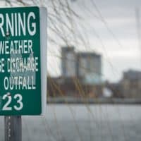 A MWRA wet weather sewage discharge outfall warning on the Charles River by the outlet of Boston's Muddy River (Robin Lubbock/WBUR)
