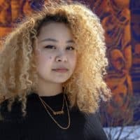 Artist Sneha Shrestha, at her mural "For Cambridge With Love From Nepal" in Cambridge. (Robin Lubbock/WBUR)