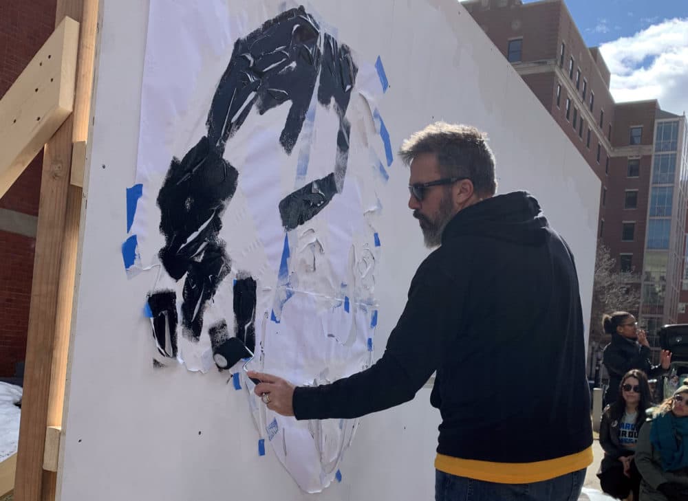 Manny Oliver starts a pop-up art installation with a stencil of Albert Einstein. (Simón Rios/WBUR)