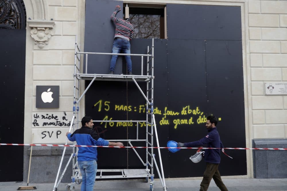 Men work to install wooden boards on the damaged window of an Apple store on the Champs-Elysees avenue in Paris on March 17, 2019, a day after the 18th consecutive Saturday of demonstrations called by the yellow vest movement. (Geoffroy Van Der Hasselt/AFP/ Getty Images)