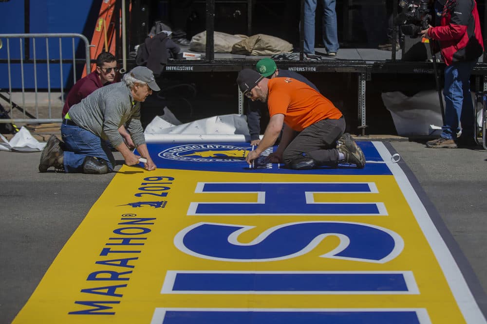 Workers lay down the finish line on Boylston Street in Copley Square for the 2019 Boston Marathon. (Jesse Costa/WBUR)