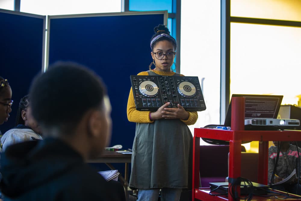 Kyara Andrade presents a mixer and explains the concepts of segueing between songs using a fader to students. (Jesse Costa/WBUR)