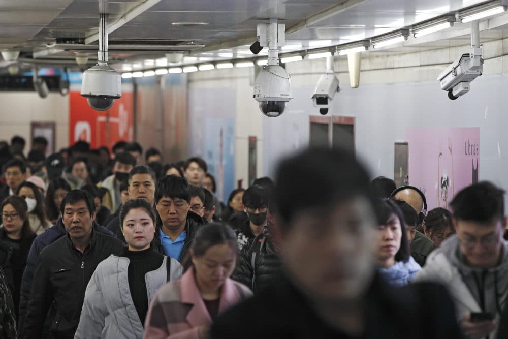 Commuters walk by surveillance cameras installed near a subway station in Beijing, Feb. 26, 2019. The Chinese government has used facial recognition and other technology to tighten control over society. (Andy Wong/AP)
