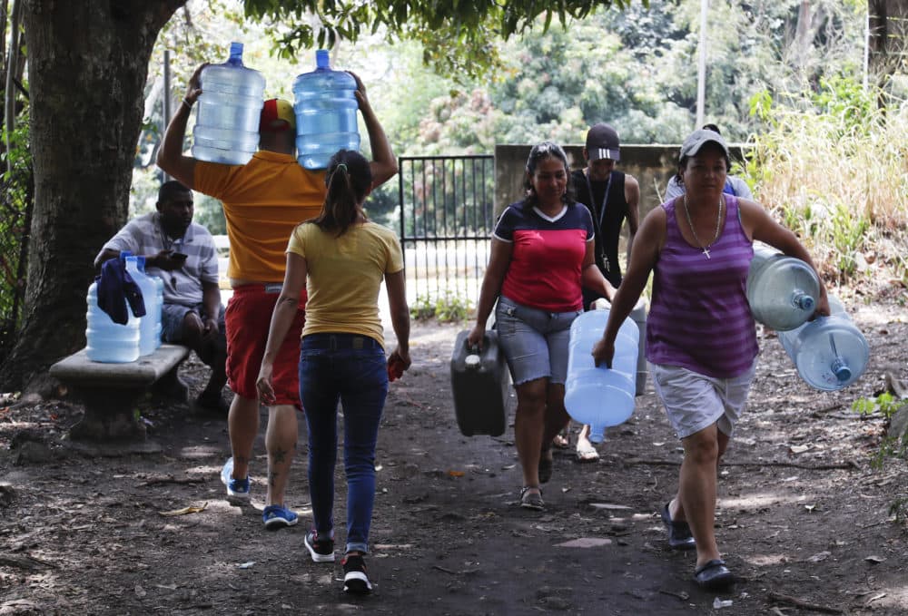 People carry containers to fill with water in Avila National Park during rolling blackouts that have cut many off from running water in Caracas, Venezuela, on March 13, 2019. (Eduardo Verdugo/AP)