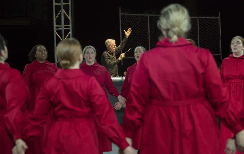 David Angus conducts as Handmaids circle on the stage at a rehearsal of "The Handmaid's Tale." (Robin Lubbock/WBUR)