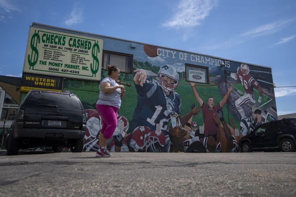 A woman walks past a mural depicting Boston as it's commonly referred to as the "City of Champions." (Jesse Costa/WBUR)