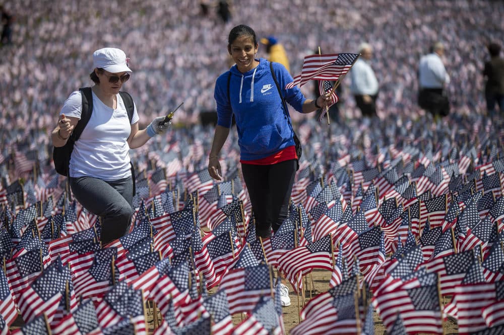 Volunteers Valerie Savin, left, and Sacha Santimano look for bare spots to plant flags. (Jesse Costa/WBUR)