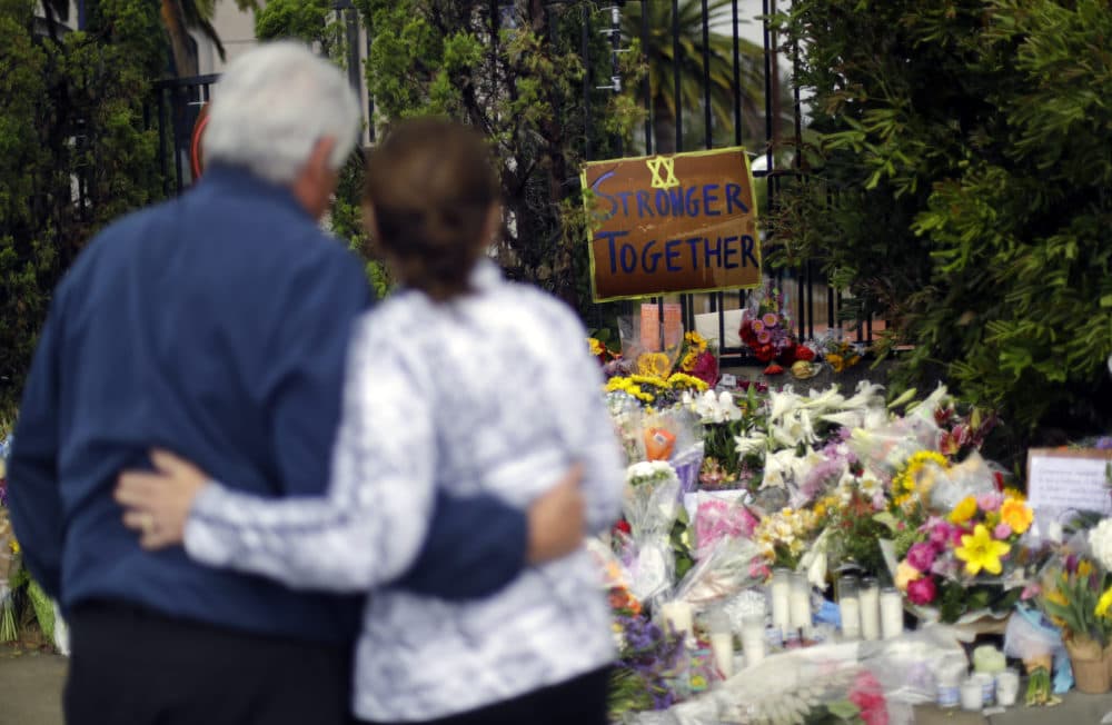 A couple embrace near a growing memorial across the street from the Chabad of Poway synagogue in Poway, Calif., on Monday,, April 29, 2019. (Greg Bull/AP)