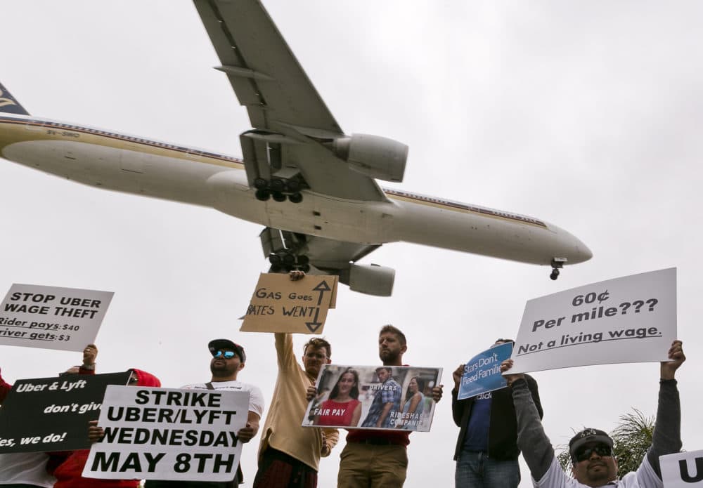 On Wednesday, drivers for ride-hailing companies Uber and Lyft hold a rally at a park near Los Angeles International Airport. Some Uber and Lyft drivers turned off their apps to protest what they say are declining wages as both companies rake in billions of dollars from investors. (Damian Dovarganes/AP)