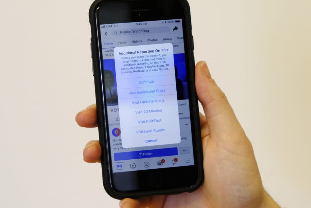 In this Tuesday, May 28, 2019, photo a smartphone display shows a Facebook notice that additional reporting is available on a doctored video posted last week showing House Speaker Nancy Pelosi appearing to slur her words in San Francisco. (Eric Risberg/AP)