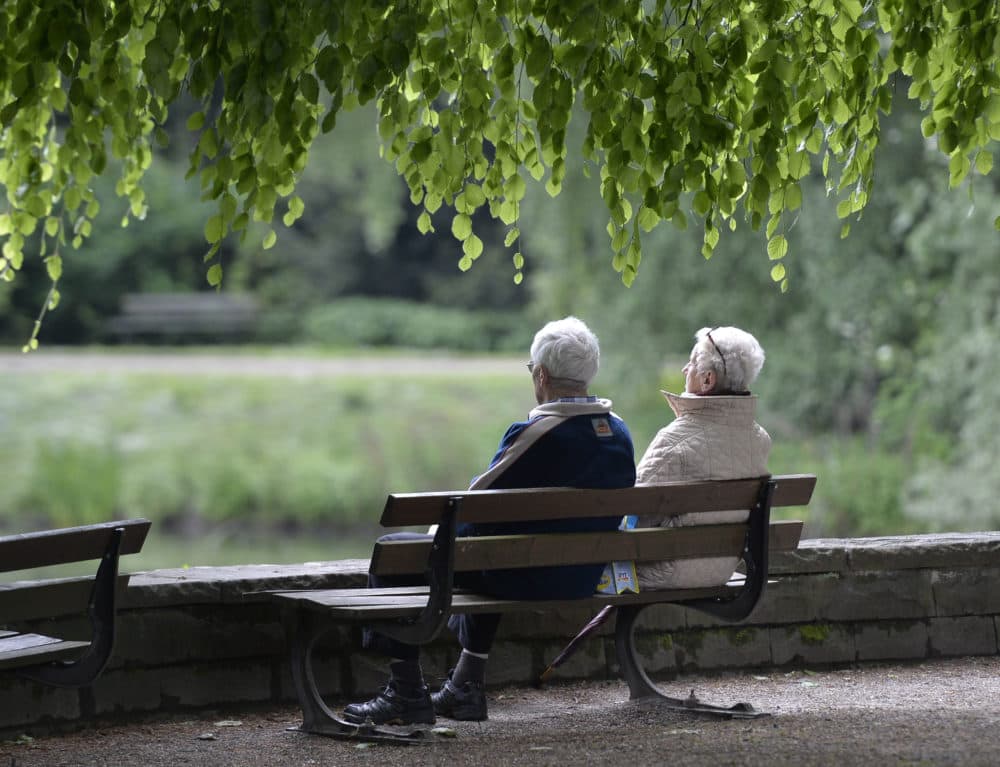 An elderly couple sits on a bench in a park in this 2014 file photo. (Martin Meissner/AP)