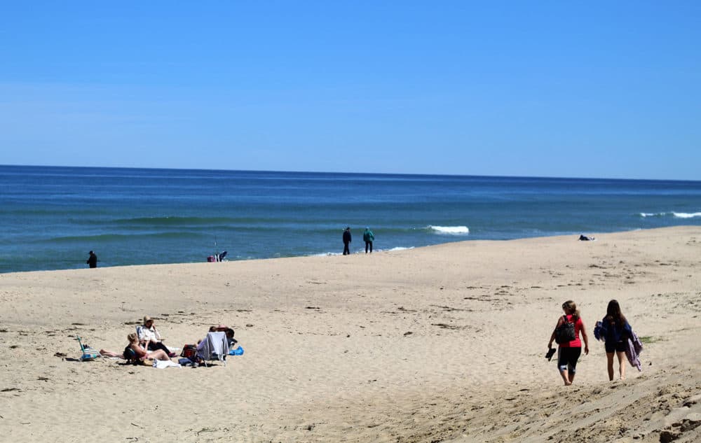 Two people walk along Newcomb Hollow Beach in Wellfleet. (Quincy Walters/WBUR)