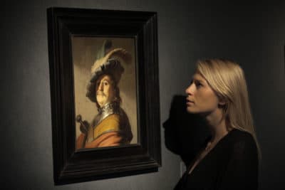 An auction house worker poses in front of a Rembrandt masterpiece entitled "A Bust of a Man in a Gorget and Cap" that was sold at auction for 8.4 million pounds in London 2012. (Lefteris Pitarakis/AP)