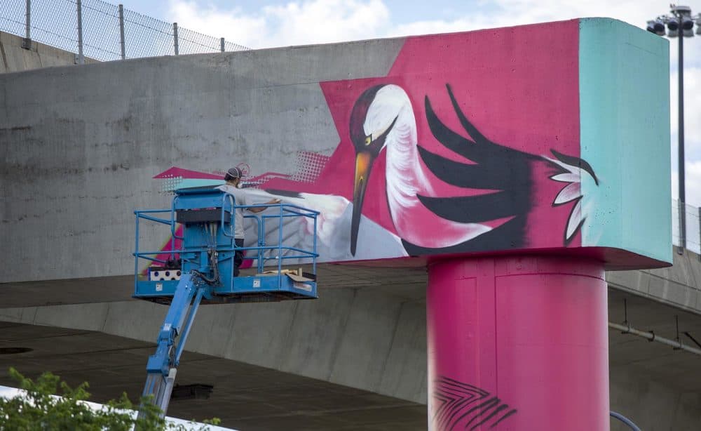 High up on a beam supporting I-93, muralist Victor "Marka27" Quiñonez works the crane at the top of his new piece. (Robin Lubbock/WBUR)