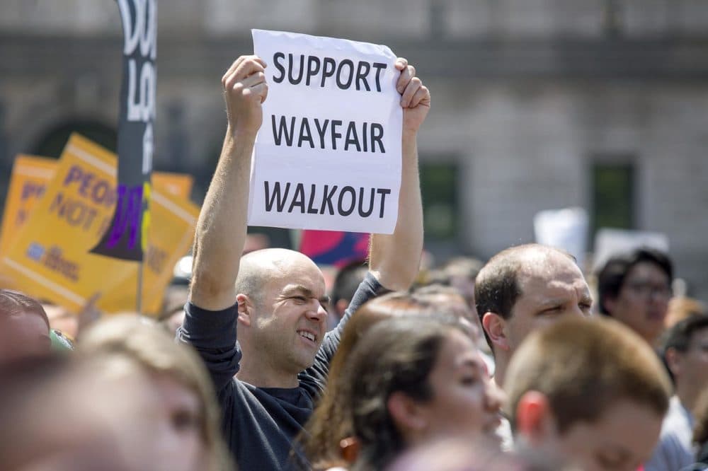 A man in Copley Square holds a sign in support of the Wayfair walkout. (Robin Lubbock/WBUR)