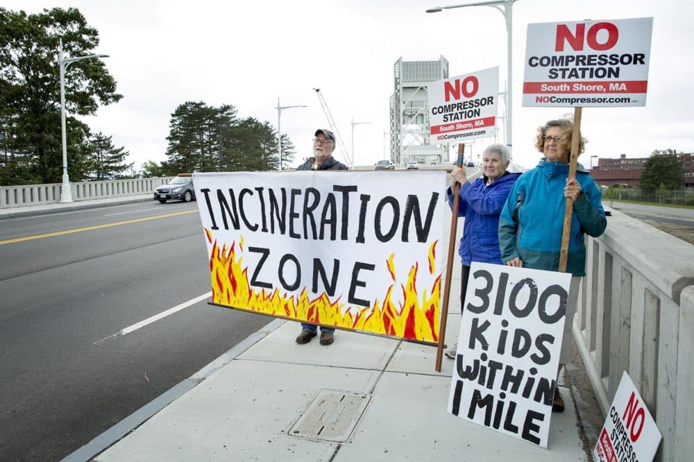 From left: Protesters John Gauley, Mernie Clifton and Margaret Bellafiore demonstrate on the Fore River Bridge, close to the site of the proposed compressor. (Robin Lubbock/WBUR)