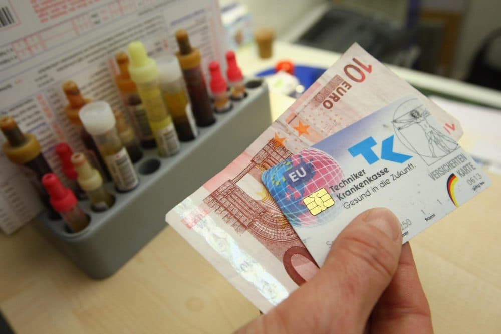 A secretary accepts 10 euros and a public health insurance card in Berlin, Germany. (Sean Gallup/Getty Images)