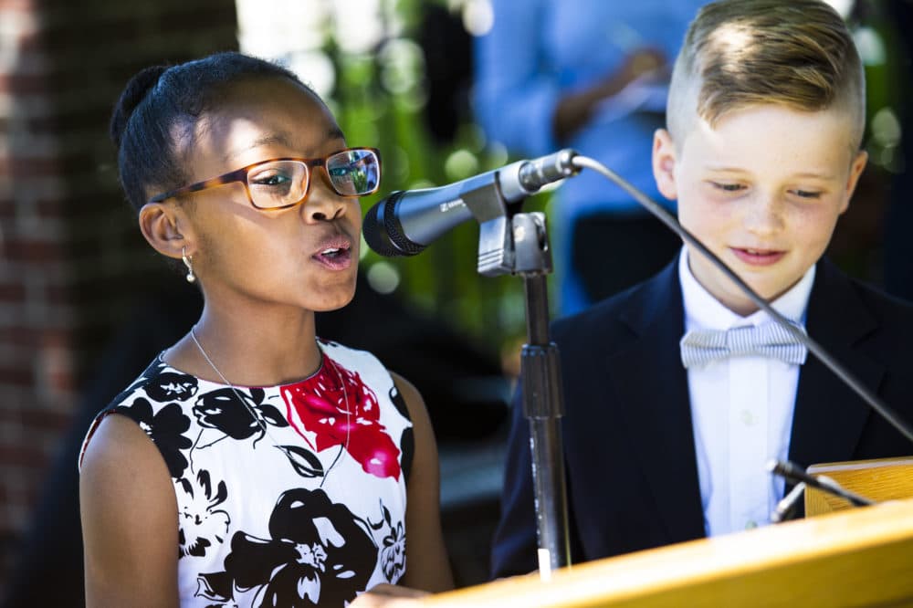 Jasmine Hagbourne, left, and Liam Brady welcome community members to the unveiling ceremony of the Medford Slavery Memorial in Salem Street Burying Ground. (Erin Clark for WBUR)