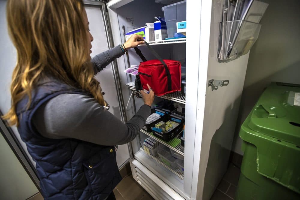 Dr. Jessie Gaeta captures vaccines stored in a refrigerator at the Healthcare for the Homeless office before loading them into the Care Zone pickup truck. (Jesse Costa / WBUR)