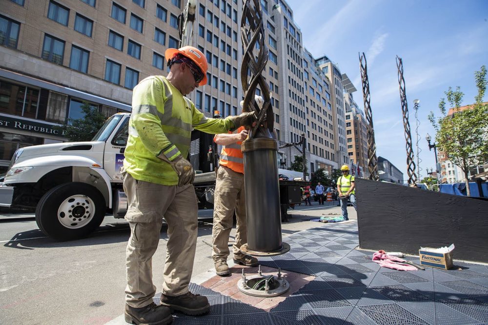 Installation workers place the final of four bronze spires into place at the site of the Boston Marathon bombing monument on Boylston Street. (Jesse Costa/WBUR)