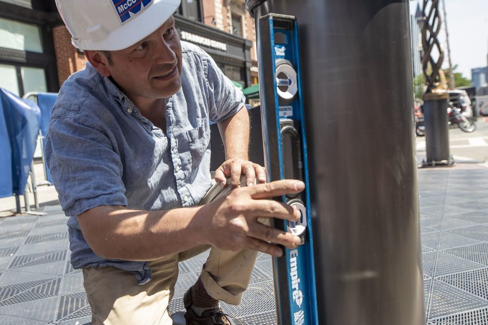 Artist Pablo Eduardo checks how straight the second spire is with a level. (Jesse Costa/WBUR)