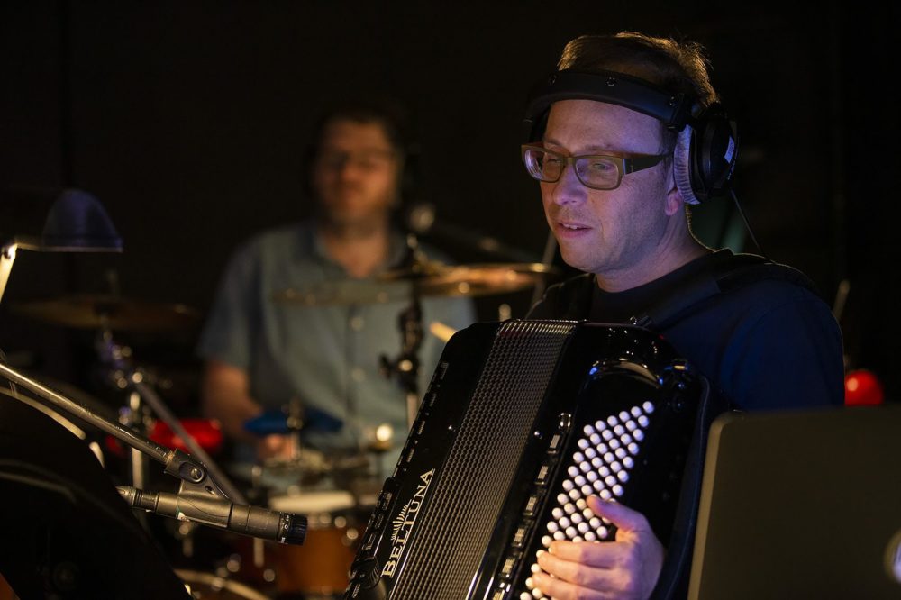 At a recent rehearsal for the circus workshop, Peter Bufano plays his accordion as Mike Dobson plays drums in the background. (Jesse Costa/WBUR)