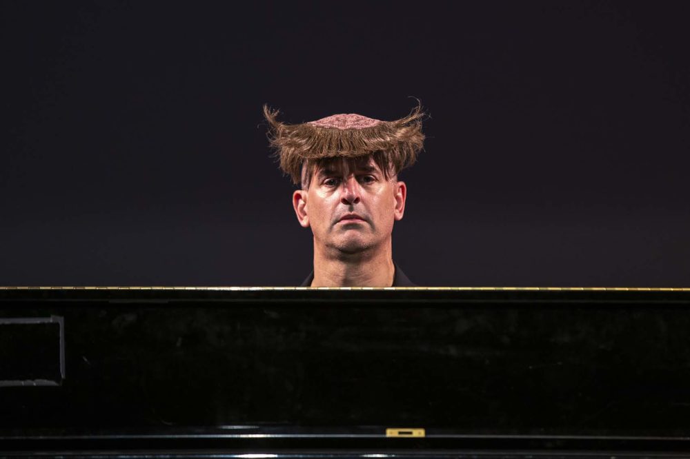 Comedian Joel Jeske's wig flips up from behind after he sneezes. (Jesse Costa/WBUR)