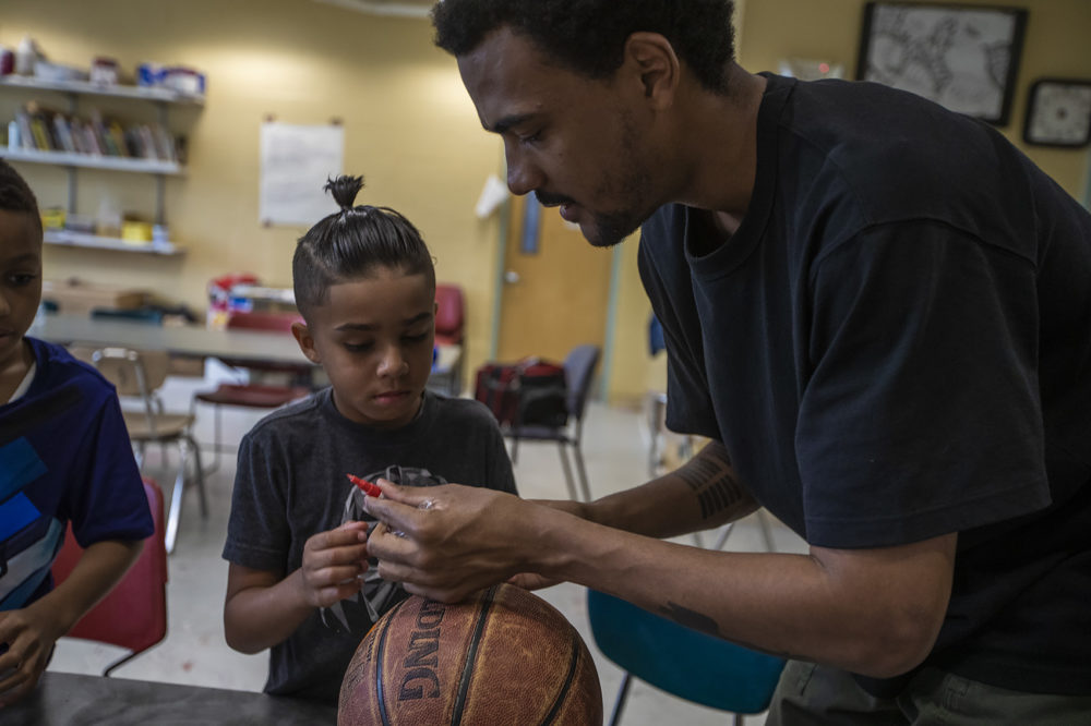 Artist Shaka Dendy prepares markers for a group of 8 and 9-year-old boys at the Yawkey Boys and Girls Club in Roxbury as they decorate old basketballs, which he will use to create a large scale public sculpture. (Jesse Costa/WBUR)