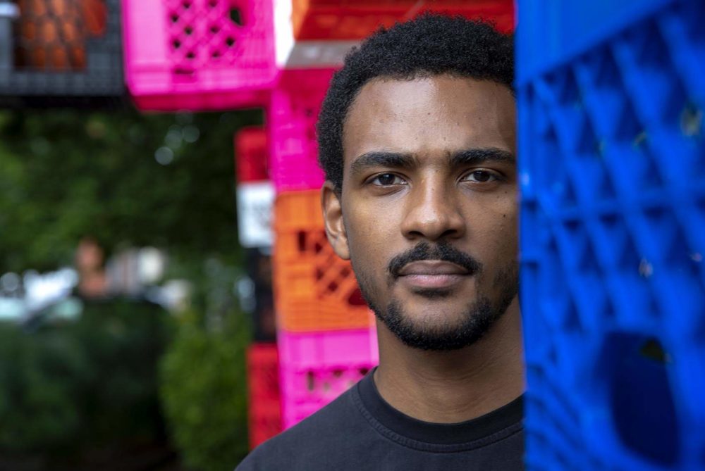 Artist Shaka Dendy stands in front of his completed public sculpture, "Gestures of Incompleteness," in front of the Boston Center for the Arts in the South End. (Robin Lubbock/WBUR)
