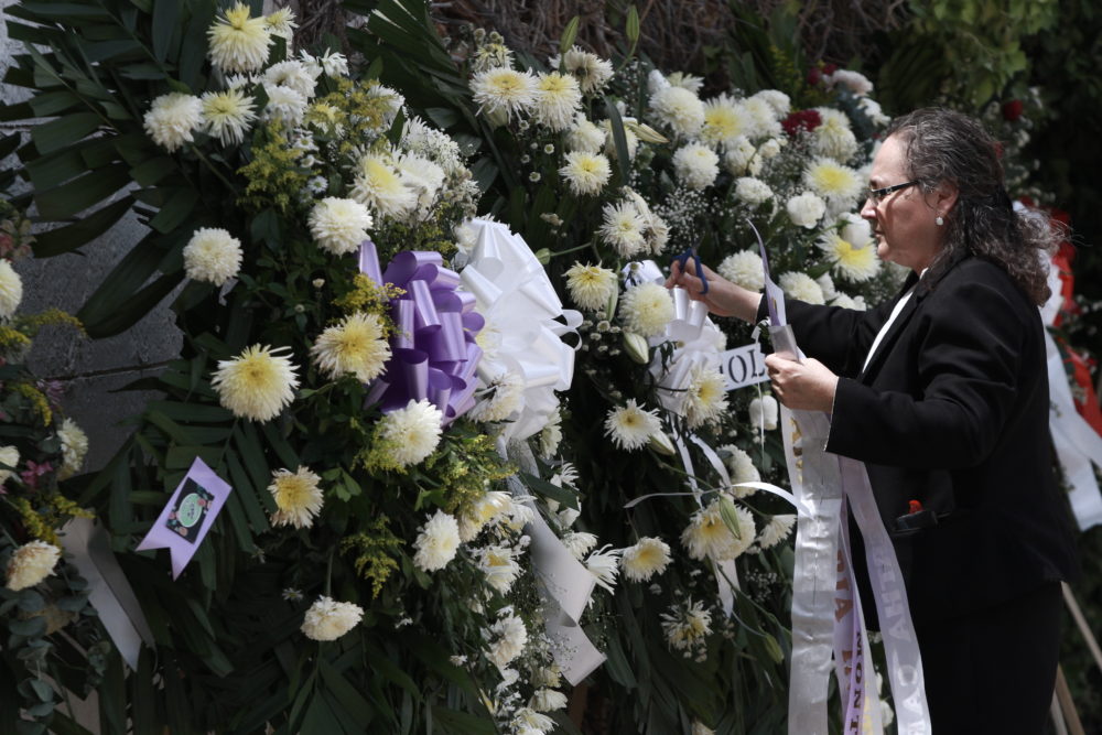 A woman places a ribbon on a flower arrangement, at the funeral of elementary school principal Elsa Mendoza, of one of the 22 people killed in a shooting at a Walmart in El Paso, in Ciudad Juarez, Mexico, on Aug. 8. (Christian Chavez/AP)