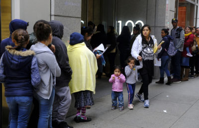 In this Jan. 31, 2019, file photo, hundreds of people overflow onto the sidewalk in a line snaking around the block outside a U.S. immigration office with numerous courtrooms in San Francisco. Santa Clara and San Francisco have filed suit against the Trump administration over its new controversial "public charge" rule that restricts legal immigration. This lawsuit is the first after the Department of Homeland Security's announcement Monday, Aug. 12, 2019, that it would deny green cards to migrants who use Medicaid, food stamps, housing vouchers or other forms of public assistance. (Eric Risberg/AP)