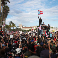 Rapper Bad Bunny (holding flag), singer Ricky Martin (black hat) and rapper Residente (blue hat) join demonstrators protesting against Ricardo Rosselló. (Joe Raedle/Getty Images)