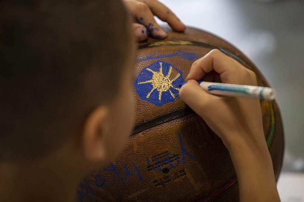 A boy decorates old basketballs for artist Shaka Dendy's installation. (Jesse Costa/WBUR)