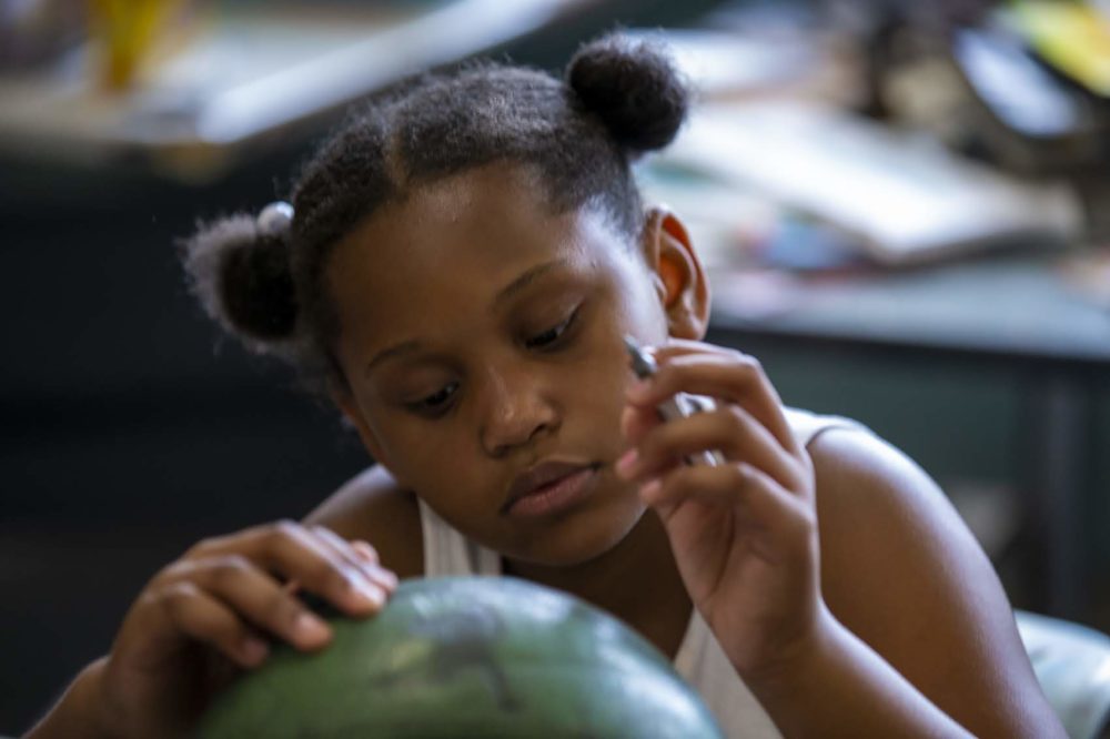 Eight-year-old Za'nii Morris decorates an old basketball at the Yawkey Boys and Girls Club in Roxbury. (Jesse Costa/WBUR)