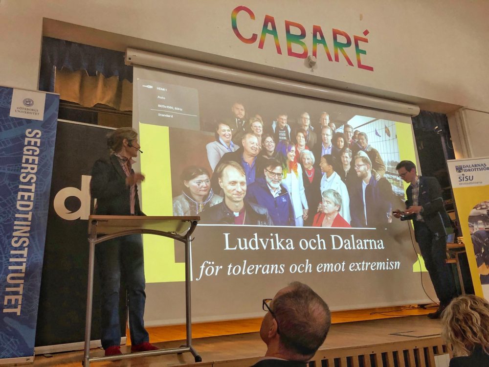 The author, left, speaks to residents of Ludvika, Sweden on May 1, 2019. In English, the slide reads: ""Ludvika and Dalarna for tolerance and against racism." (Courtesy)