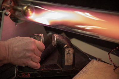 Martin Greenwald demonstrates how you can use a magnetic fields to contain and insulate a hot fusion plasma. Here the magnet pushes the bright plasma away from the wall of the glass tube. (Robin Lubbock/WBUR)