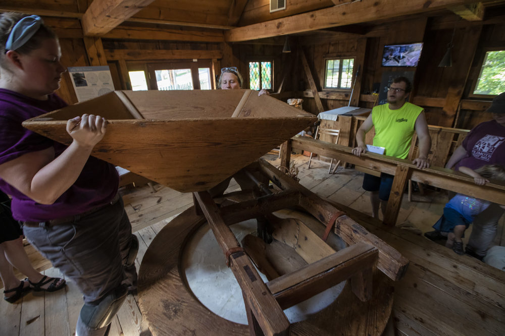 Kim VanWormer, right, and Sydney Tierney place the hopper into position as visitors watch from the side. (Jesse Costa/WBUR)