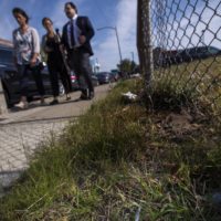 Boston City Councilor Annissa Essaibi George, WBUR reporter Deborah Becker and state Sen. Nick Collins walk past a used syringe and needle left in the grass on Bradston Street. (Jesse Costa/WBUR)